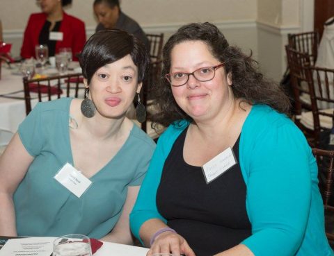 Two women pose at a table